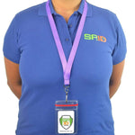 Person wearing a blue polo shirt with an "SPID" logo and a purple lanyard that holds an ID badge labeled "Specialist ID, Inc." around their neck, neatly secured in one of their Custom Heavy Duty Vinyl Vertical Badge Holder w/ Resealable Zip Top (1815-1110).