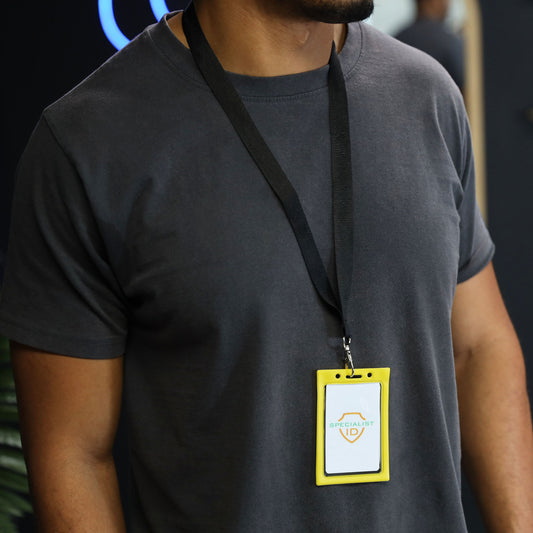 Person wearing a plain dark gray t-shirt and a lanyard with a Vertical Vinyl Color Frame Badge Holder (P/N 1820-300x) around their neck.