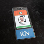 A photo of a Custom Printed BadgeBottoms® Vertical (Badge Holder & Badge Buddy IN ONE!!) displaying an ID badge and an RN card. The ID badge features a headshot with the name "Raphael Smith" and the title "Operations" below it, while the blue RN card has white letters.