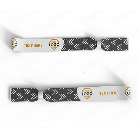 The Custom Printed Wristband features black and white dye-sublimated arrow patterns, customizable logo areas, and a "TEXT HERE" section for personalized messages—perfect as event wristbands or unique accessories.