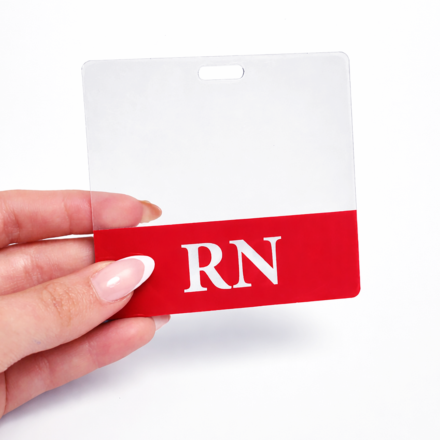 A hand holds a Clear RN Badge Buddy - Horizontal ID Badge Backer for Nurses - Double Sided Print with a red and white design and the letters "RN" clearly displayed on it. Sold by Specialist ID