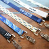 Five Custom Double Ended Lanyards with 2 clips, each customized with unique logos and full color designs, are shown side by side on a wooden surface. Ideal for event ID badges and name tags, these lanyards can feature your logo, text, or artwork.