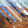 Five Custom Double Ended Lanyards with your logo, text, or artwork are displayed on a wooden surface, each featuring two metal clips for event ID badges or name tags, highlighting quality personalized printing.