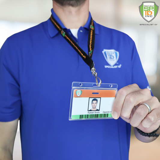 A person in a blue polo shirt holds up the Horizontal Economy Crystal Clear Card Dispenser (P/N 726-CT1), which displays an employee ID with photo, name, and title, and features a thumb notch for easy removal from its holder.