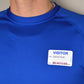 A person wearing a blue shirt with a "VISITOR" name tag that reads "Name: Edward Smith, Date: March 2021," with the text below the date partially obscured, likely using an Expiring Visitor Badge and Log Book - 480 Badges (05741).