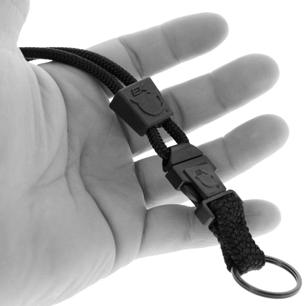 A close-up shows a hand holding a black braided EK Lanyard Plus with Detachable Key Ring (10028) by EK USA, featuring a metal ring and clasp, and a detachable key ring for added convenience.
