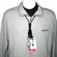 A gray zip-up jacket with a Black EK Breakaway Lanyard with Detachable ID Hook And Key Ring (10230) by EK USA around the neck, holding an ID badge and an "RN" tag. The jacket has "Specialist ID" embroidered on the left side.