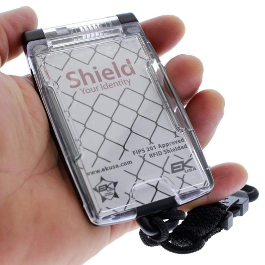 A hand holds a Black EK One Hander Holder with Detachable Lanyard (10983) by EK USA with "Shield Your Identity" text. The heavy-duty FIPS 201 approved holder features a logo and is attached to a detachable lanyard.