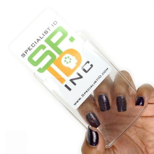 Hand with black-painted nails holding a Vertical Heavy Duty Vinyl ID Badge Holder with Reinforced Edges and Orange Peel Texture (1815-1100). The transparent holder, featuring reinforced edges, contains a white card with the text "Specialist ID" and "SP ID INC," along with a website address.