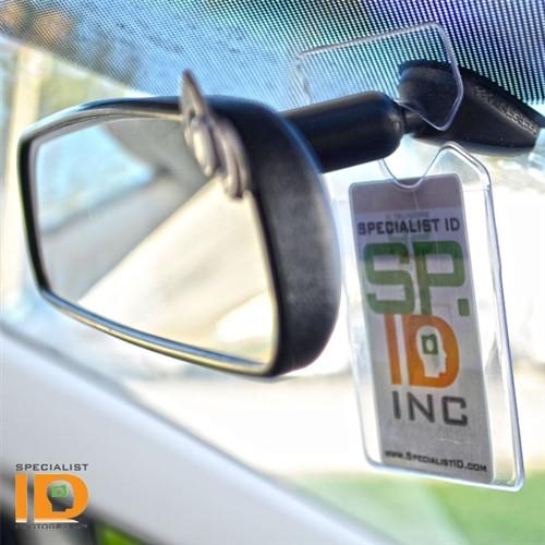 A Clear Rigid Vinyl Vertical Vehicle Parking Pass Hang Tag Holder (1840-3600) featuring a clear vinyl hang tag that doubles as an ID badge holder, displaying a Specialist ID, Inc. badge.