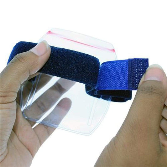 Two hands adjust a black and blue strap attached to a clear plastic shield, similar to Vertical Armband ID Badge Holders with Zipper Top (504-ARZB & 504-ARZW).