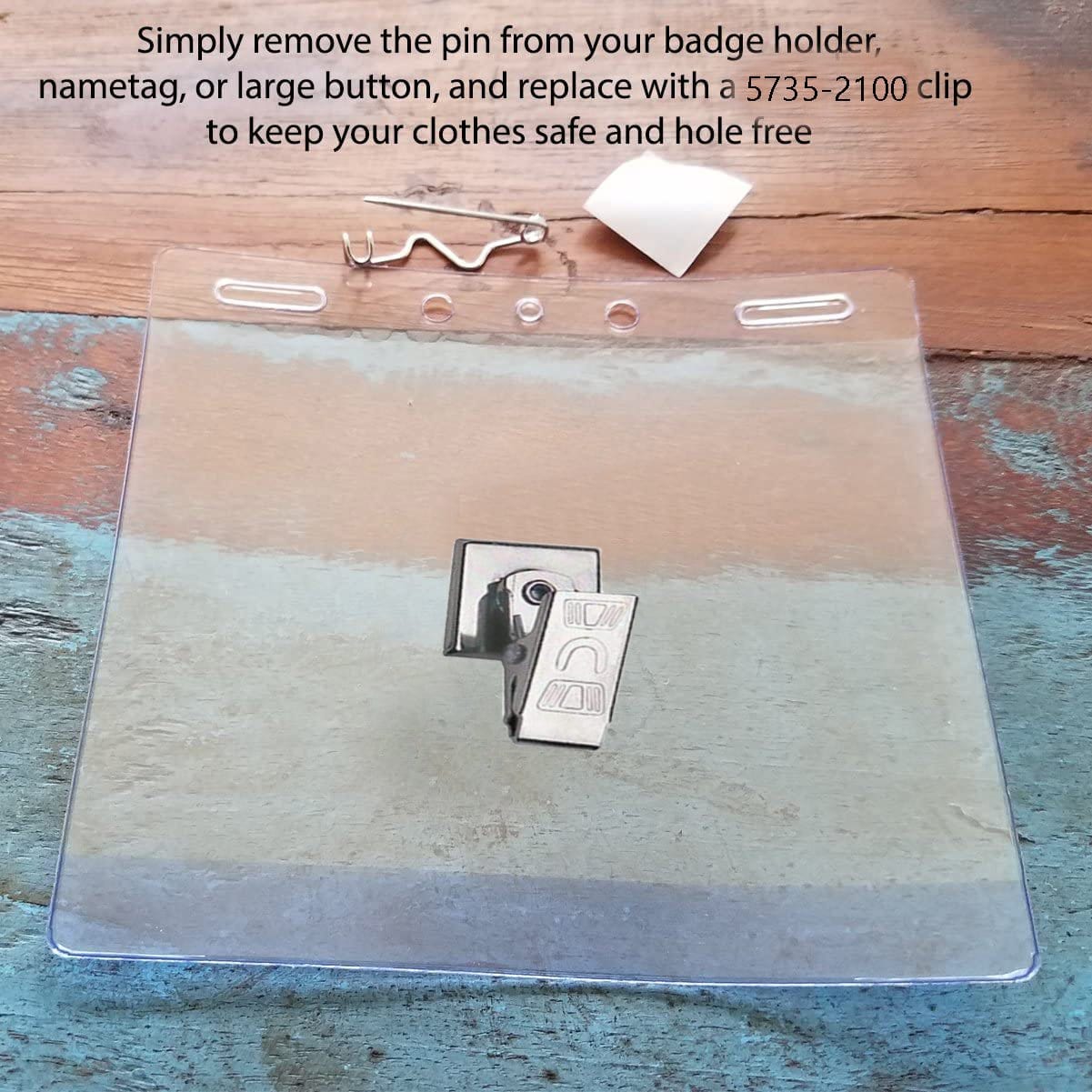 A transparent badge holder is displayed on a wooden surface with a metal clip and a white attachment above it. Instructions for replacing a pin with a Pressure-Sensitive Nickel-Plated Clip, Embossed "U" Bulldog Clip with Adhesive Back 5735-2100 are written on the image.