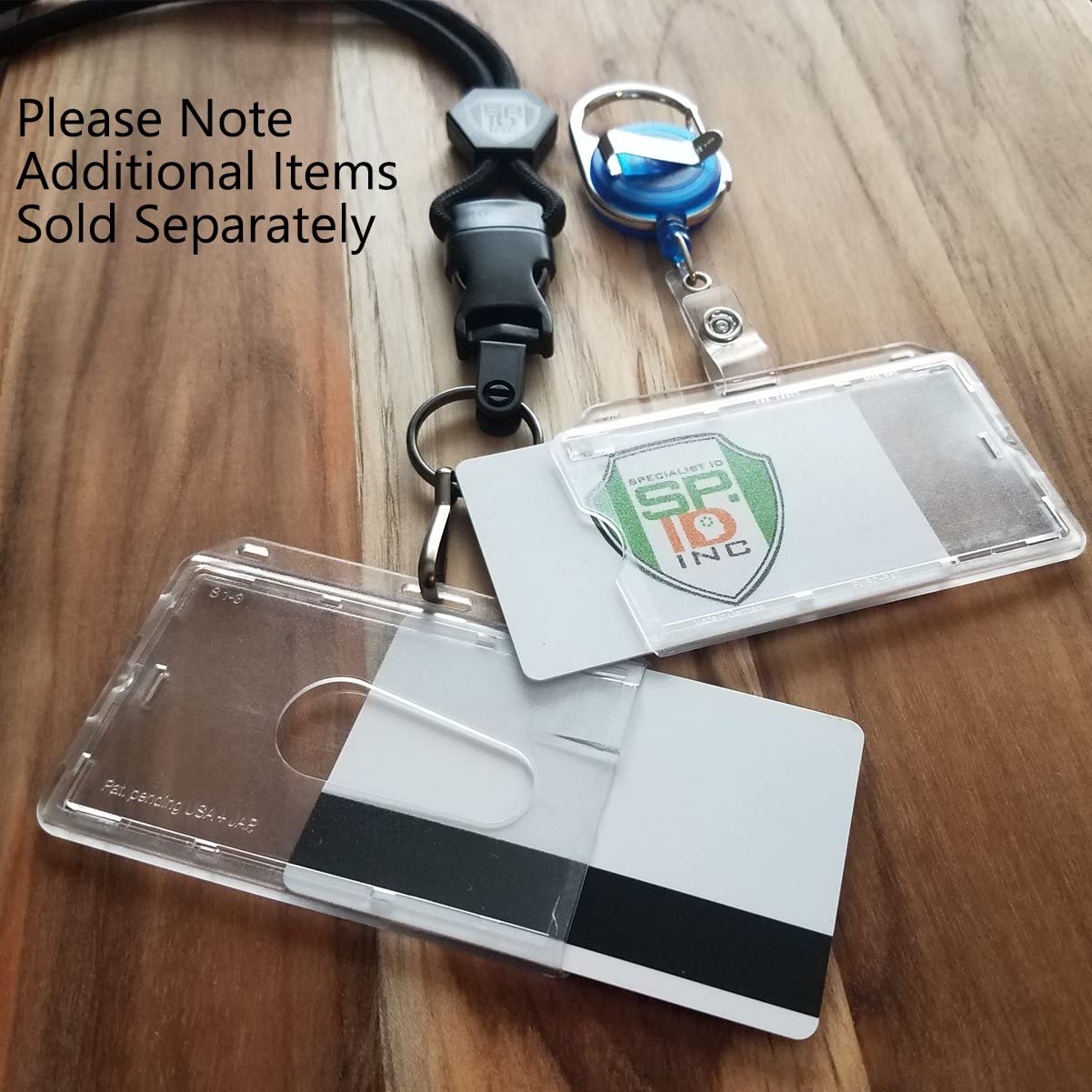 A Polycarbonate Slim Horizontal Clear Rigid ID Card Dispenser - Clear Hard Plastic - with Thumb Notch and a retractable keychain is displayed on a wooden surface. Note on the image says, "Please Note Additional Items Sold Separately.