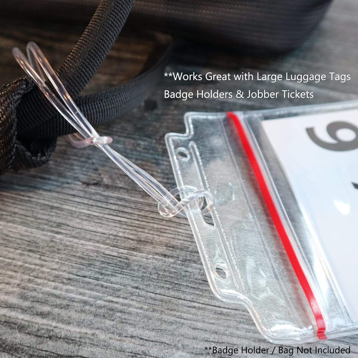 Close-up of a clear plastic luggage tag holder looped through a badge holder on a black strap. Text on the image: "Works Great with Extra Long 9" Luggage Tag Loops - Clear Worm Loops for Luggage Tags (2410-2100) Badge Holder/Bag Not Included".