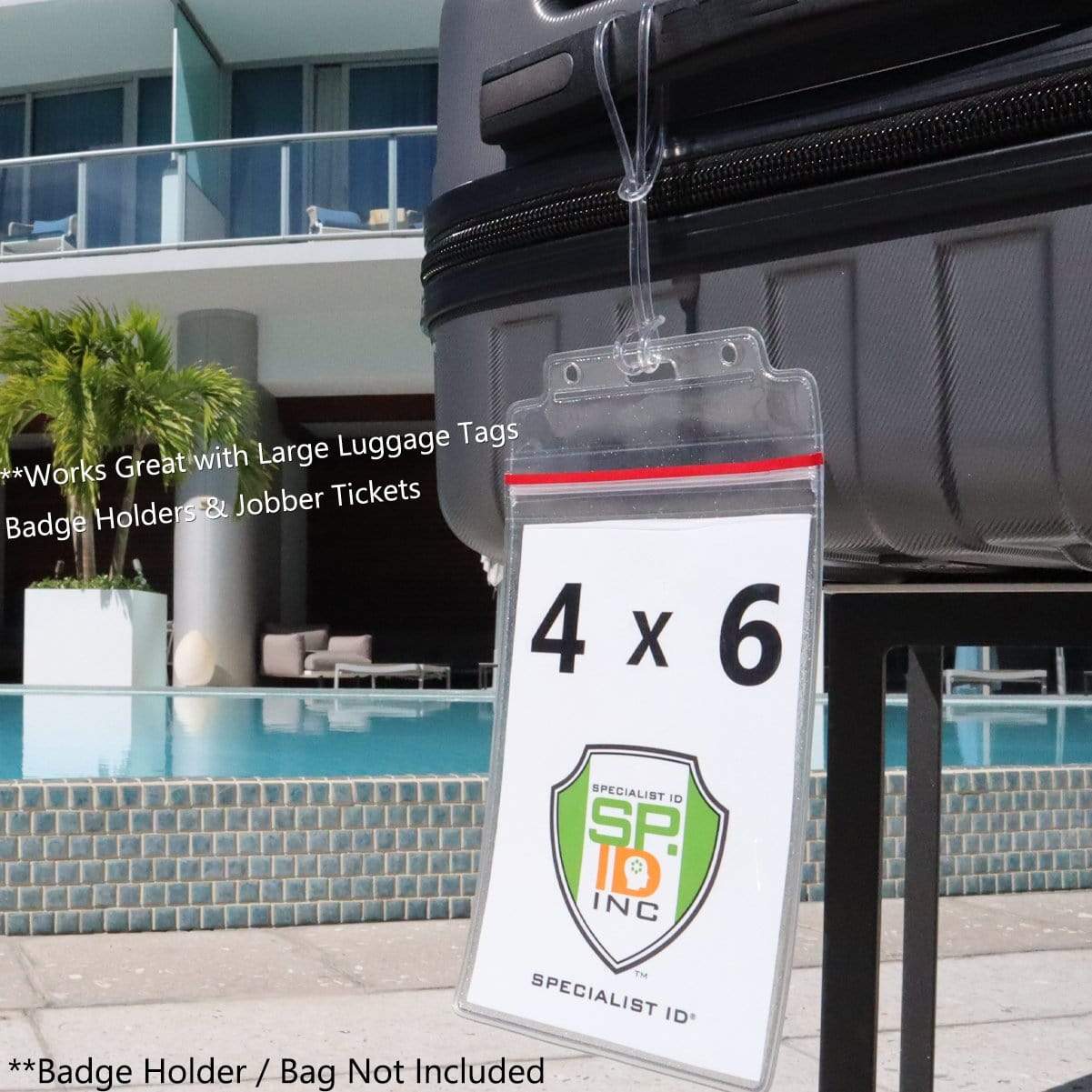 A clear luggage tag holder with a "4 x 6" card inside is attached to a suitcase using an Extra Long 9" Luggage Tag Loops - Clear Worm Loops for Luggage Tags (2410-2100). The background showcases an outdoor setting with a swimming pool and modern building. Text states badge holder/bag not included.