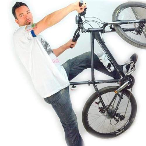 A person in a white t-shirt and jeans, sporting a Vertical Arm Badge Holder with Elastic Band And Zip Lock Seal (ABH-V-BLU-ZIP) on their wrist, performs a wheelie on a black mountain bike against a plain white background.
