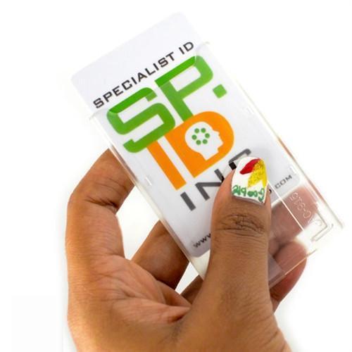 Hand holding a Top Load Rigid Clear Vertical Badge Holder (AC-915) containing a card with "Specialist ID" written on it. The person's thumbnail has a colorful design.