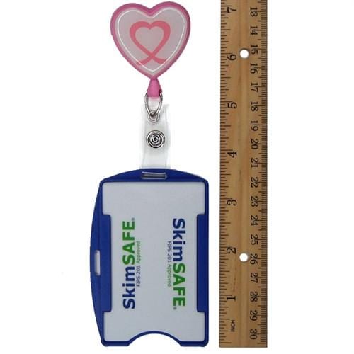 An ID badge holder with a blue clip and "SkimSAFE FIPS 201 RFID Blocking Single Card ID Holder (P/N AH-200)" printed on it, next to a 12-inch ruler and an RFID blocking retractable badge reel with a heart design.
