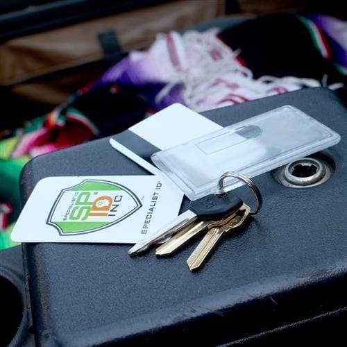A set of keys with a Two Card Vertical Clear Rigid Plastic Fuel Card and Badge Holder with Keychain (SPID-1220), a white card, and a business card from "Keypoint SPI, Inc." rest on a black surface with a colorful cloth in the background.