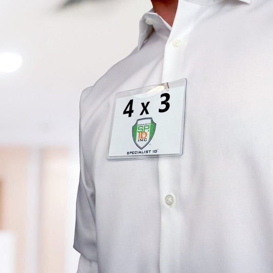 Close-up of a person wearing a white shirt with a 4 x 3 Horizontal Event Badge Holder with Clothing Friendly Bulldog Clip - Clear Vinyl, Horizontal & Durable (SPID-1440) displaying a card labeled "4 x 3" and "Specialist ID," attached using a clothing-friendly bulldog clip.