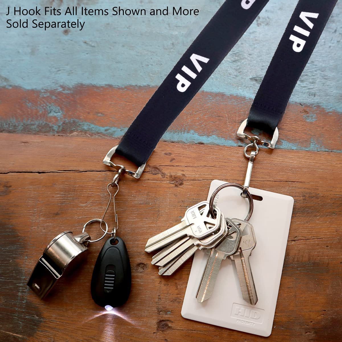 Two Black VIP Lanyards (SPID-2020-BLK) with silver attachments: one holding a whistle and small flashlight, the other holding keys and a white access card. Featuring a safety breakaway feature, these black lanyards ensure convenience and security. Text at the top notes attachments are sold separately.