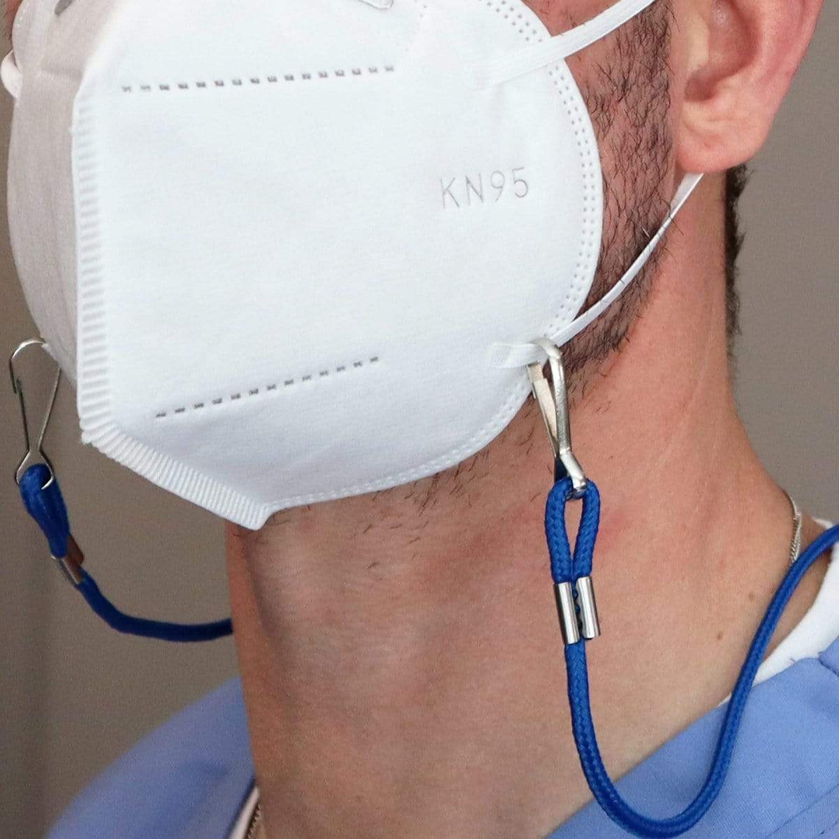A person wearing a white KN95 mask with an Adjustable Length Double Ended Lanyard - Handy & Convenient Event Badge Holder & Hanger with 2 Clips attached to the mask's ear loops, enabling easy hands-free display around their neck.