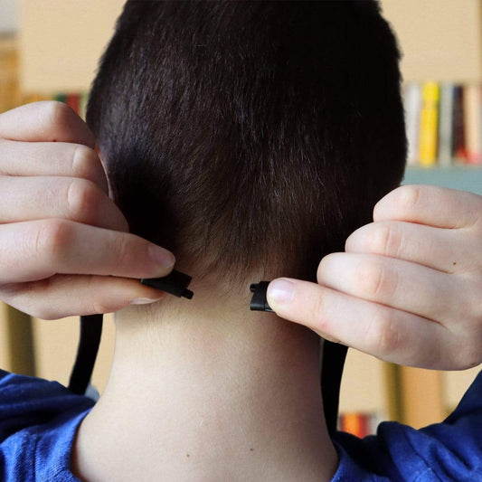 Close-up of a person fastening an Adjustable Double Ended Lanyards with Safety Breakaway Clasp and Two Bulldog Clips (2140-531X) behind their neck, with their hands near the nape and bookshelves blurred in the background.