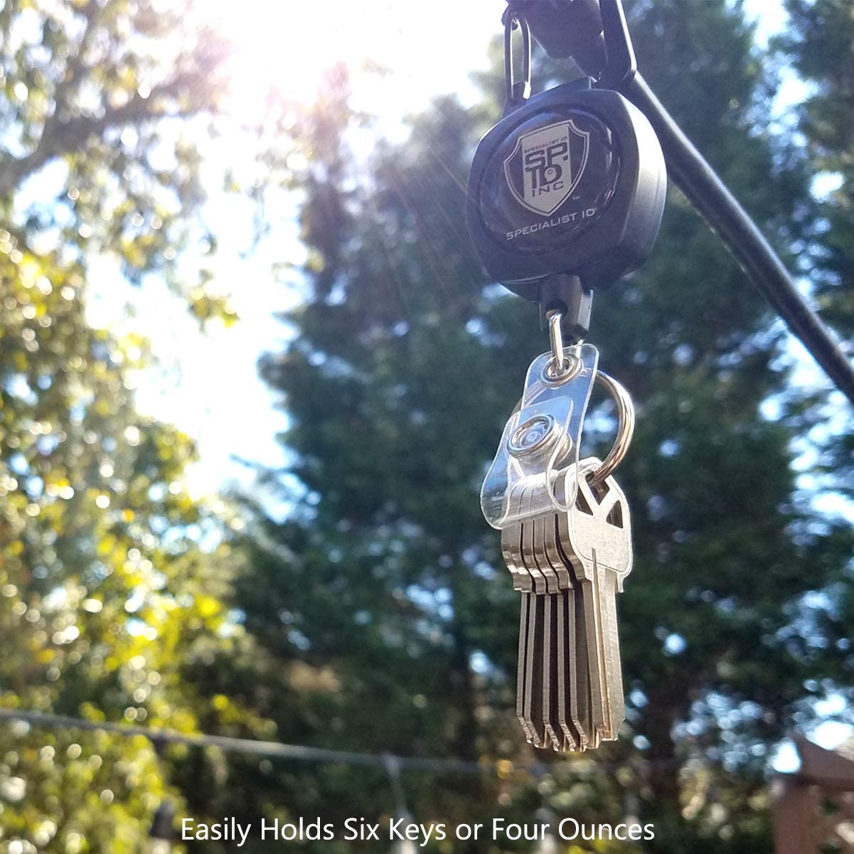A SPID Key-Bak SIDEKICK Heavy Duty Retractable Carabiner Badge Reel with ID Holder Strap & Keychain with a Specialist ID logo is shown holding six keys against an outdoor backdrop, featuring a Kevlar Retractable Cord. The text below reads, "Easily Holds Six Keys or Four Ounces.
