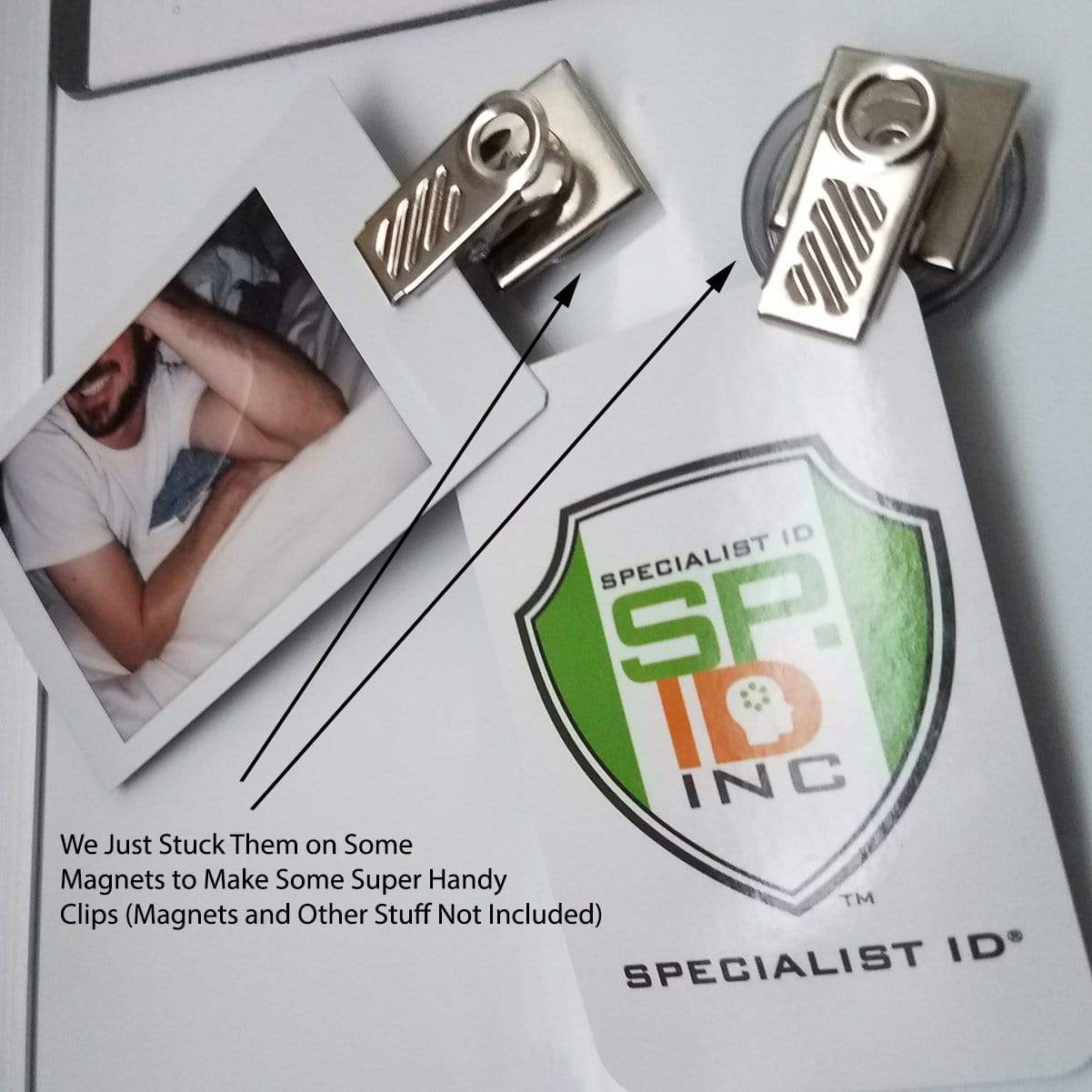 A photo and a Specialist ID card clipped onto magnets attached to a surface. The text reads, "We Just Stuck Them on Some Magnets to Make Some Super Handy Clips (Pressure-Sensitive Adhesive Back Nickel-Plated Clip, 1-Hole Ribbed Face (P/N 5735-2000), Bulldog Badge Holders, and Other Stuff Not Included).