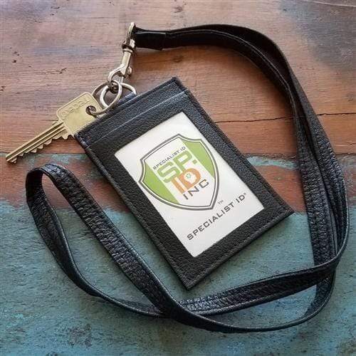 A black lanyard with a key attached to a Heavy Duty Union Made Genuine Leather ID Badge Holder Wallet & Lanyard (SPID-9590-BLACK) displaying a Specialist ID badge lies on a textured surface.