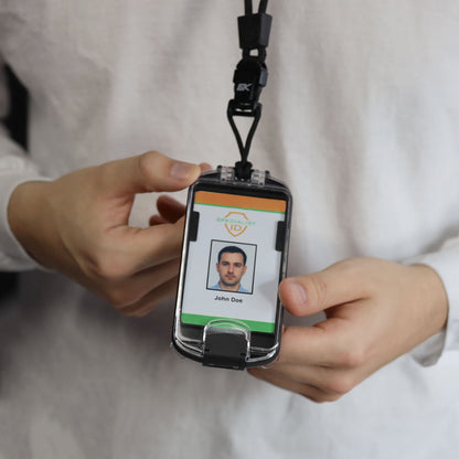 A person in a white shirt holds an EK USA Guardian RFID Blocking Hard Shell Badge Holder with Detachable Lanyard (10935), displaying an ID badge featuring a photo and the name “John Doe.” The badge is securely encased, providing both protection and professionalism.