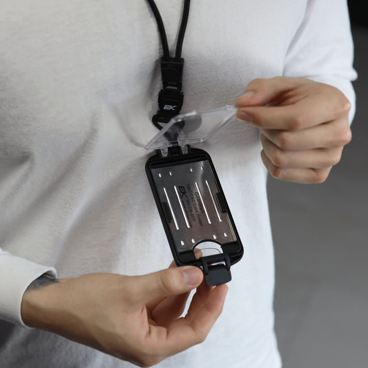 A person in a white shirt opens the EK USA Guardian RFID Blocking Hard Shell Badge Holder with Detachable Lanyard (10935), revealing a card with printed text inside.