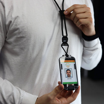 A person in a white long-sleeve shirt holds the EK USA Guardian RFID Blocking Hard Shell Badge Holder with Detachable Lanyard (10935), displaying an ID card with a photo and text.