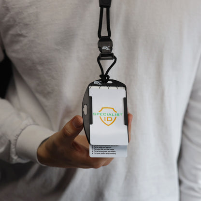 A person wearing a white shirt holds the EK USA Patriot RFID Blocking Dual Sided Badge Holder with Detachable Lanyard (10943), which displays an ID card labeled “SPECIALIST ID” with a shield logo.