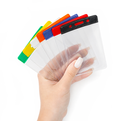 A hand holding a fan of clear plastic ID badge holder sleeves with top colorful bar tabs in green, yellow, orange, blue, red, and black, shown against a plain white background.