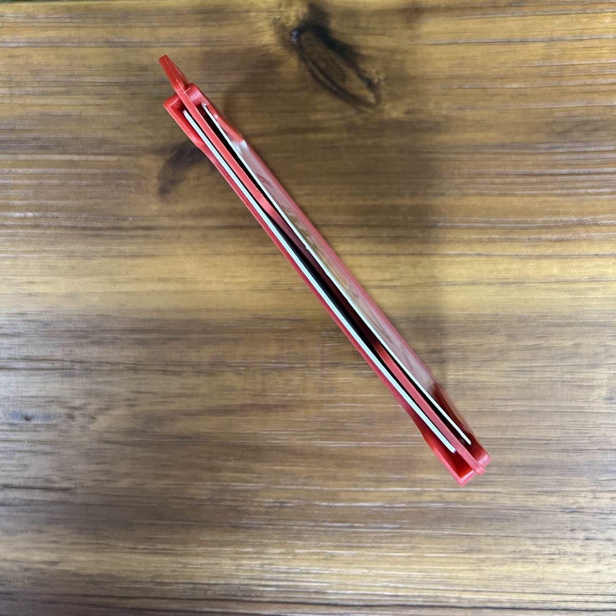 A Custom 2-Sided Rigid Vertical Multi-Card Holder (1840-308X) - Add Your Logo with its blade retracted, placed horizontally on a wooden surface, exudes a professional look.