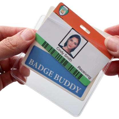 Close-up of hands holding an ID badge with the name "Cindy Smith" and photo, secured in a vinyl pocket enclosure, accompanied by a Horizontal Badge Buddy Holder (P/N 1840-5014) label.