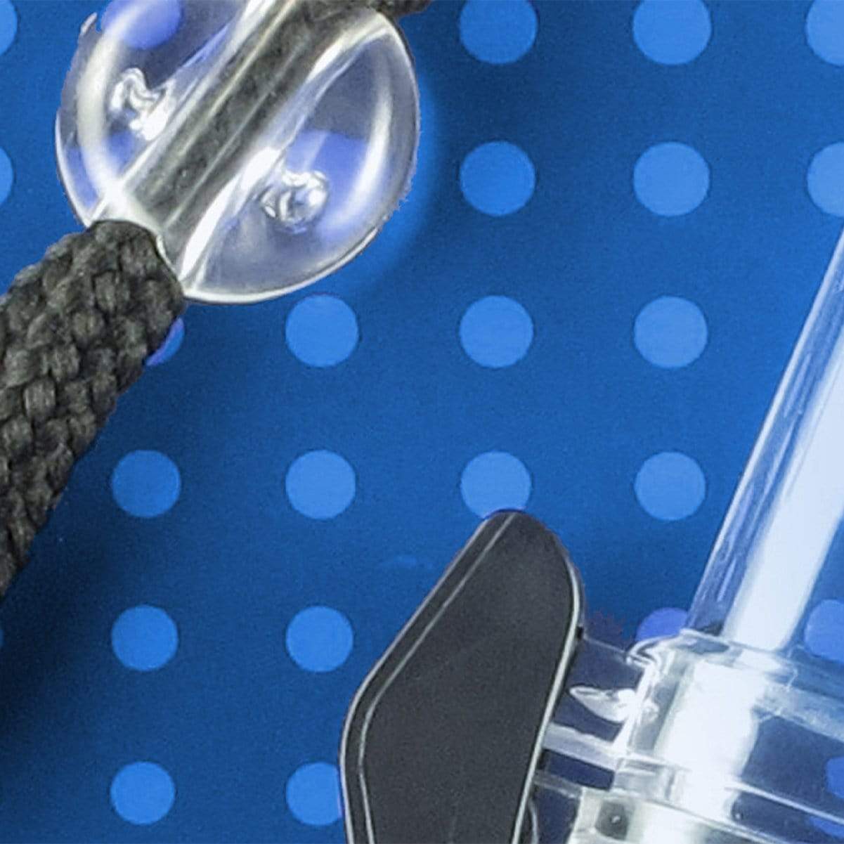 Close-up of a black cord with a clear plastic bead, resting on a blue surface with a polka dot pattern. Part of the Custom Multi-Card Clear Rigid Water Resistant Holder (1840-9000) - Add Your Logo, often used for promotional giveaways, is visible next to the cord.