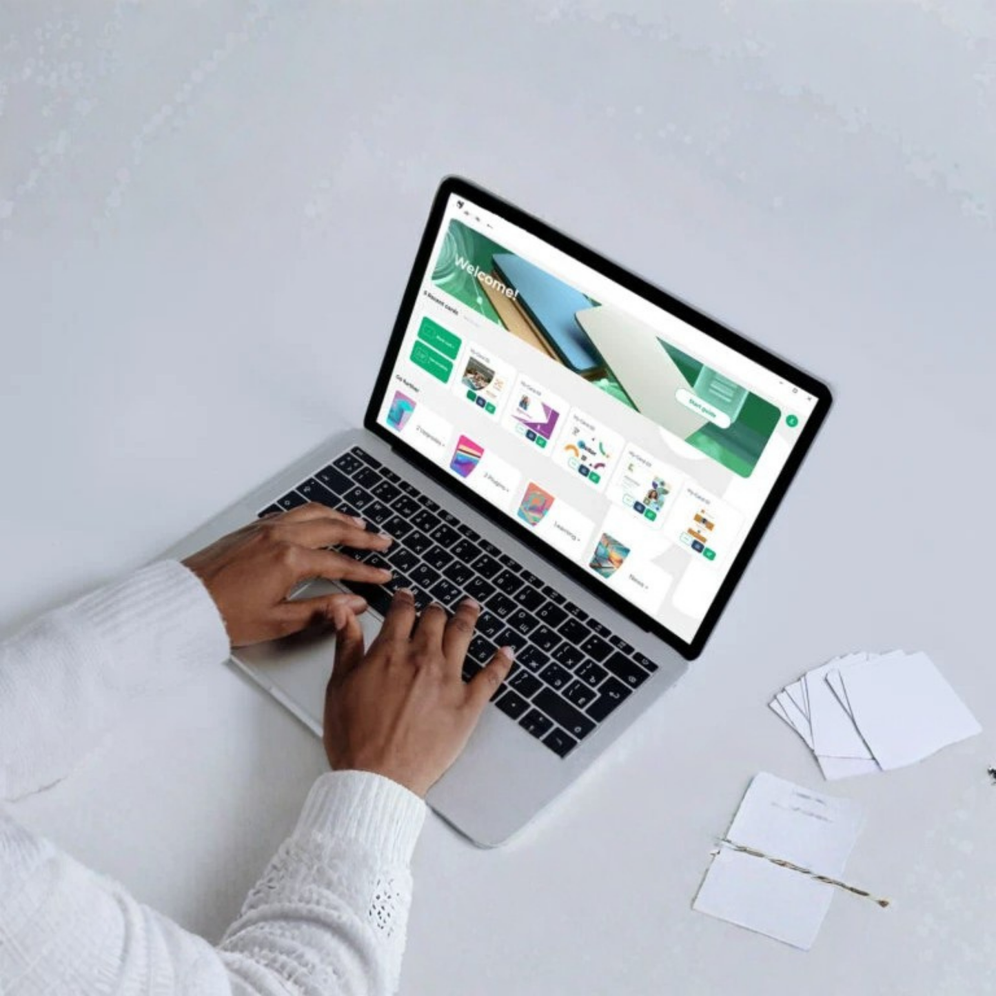 Person typing on a laptop with a digital dashboard, blank cards, and a pen nearby—perfect for using ID-ALL ID Card Software – Professional Design & Print for Windows & Mac to create and print custom ID cards.
