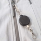 A Ski Pass Holder Retractable Heavy Duty Sport Reel (P/N 2120-4101) clipped to the zipper of a gray jacket, perfect as a ski pass holder.