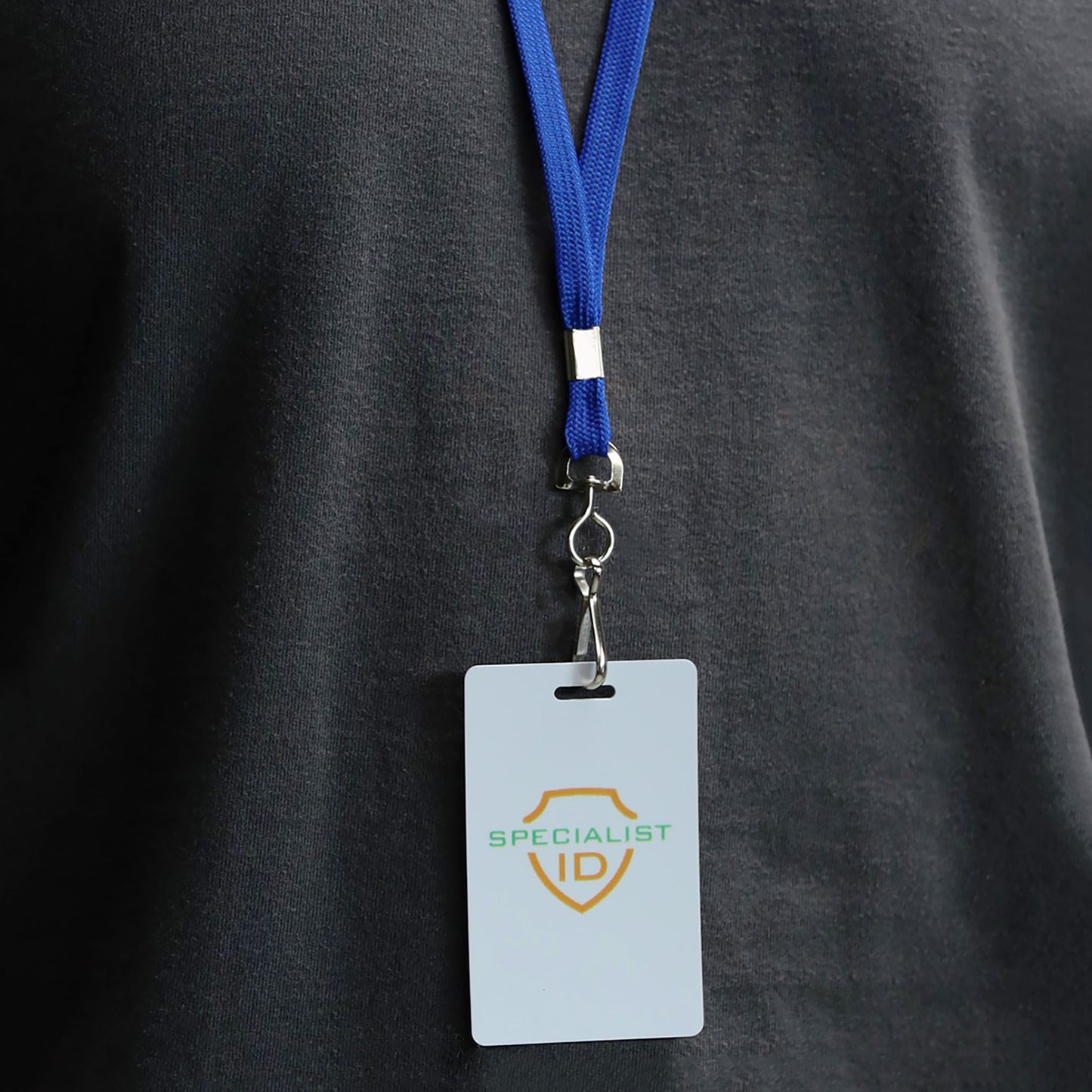 A person wearing a dark shirt has a blue Premium Economy Lanyard with Swivel Hook (3/8″ Flat Width, Non-Breakaway, 2135-350X), securely attached to a Specialist ID badge holder.