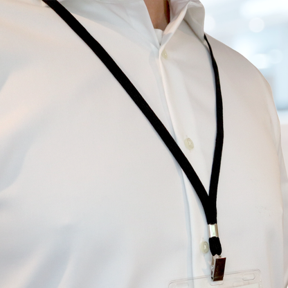 A person wearing a white button-down shirt and a Flat Braid Woven Non-Breakaway Lanyard With a Steel Bulldog Clip (P/N 2135-355X) attached to an ID badge holder. Sold by Specialist 