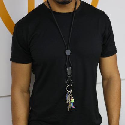 A person wearing a black t-shirt and a Heavy Duty Breakaway Round Lanyard With Detachable Key Ring (2135-454X), holding several keys on the detachable split ring, stands against a white wall with an orange design.