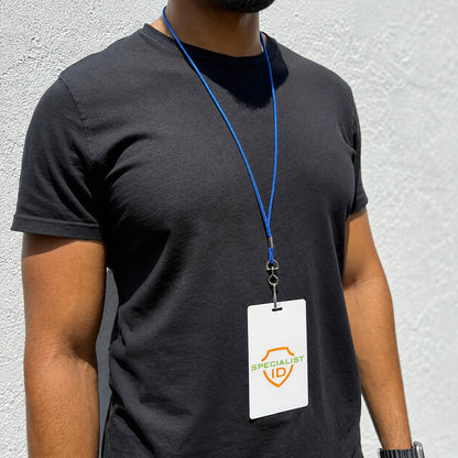 A person in a black t-shirt stands by a white wall, showing a Specialist ID badge on a blue Round Breakaway Lanyard with Swivel Hook (2137-200X) worn around their neck.