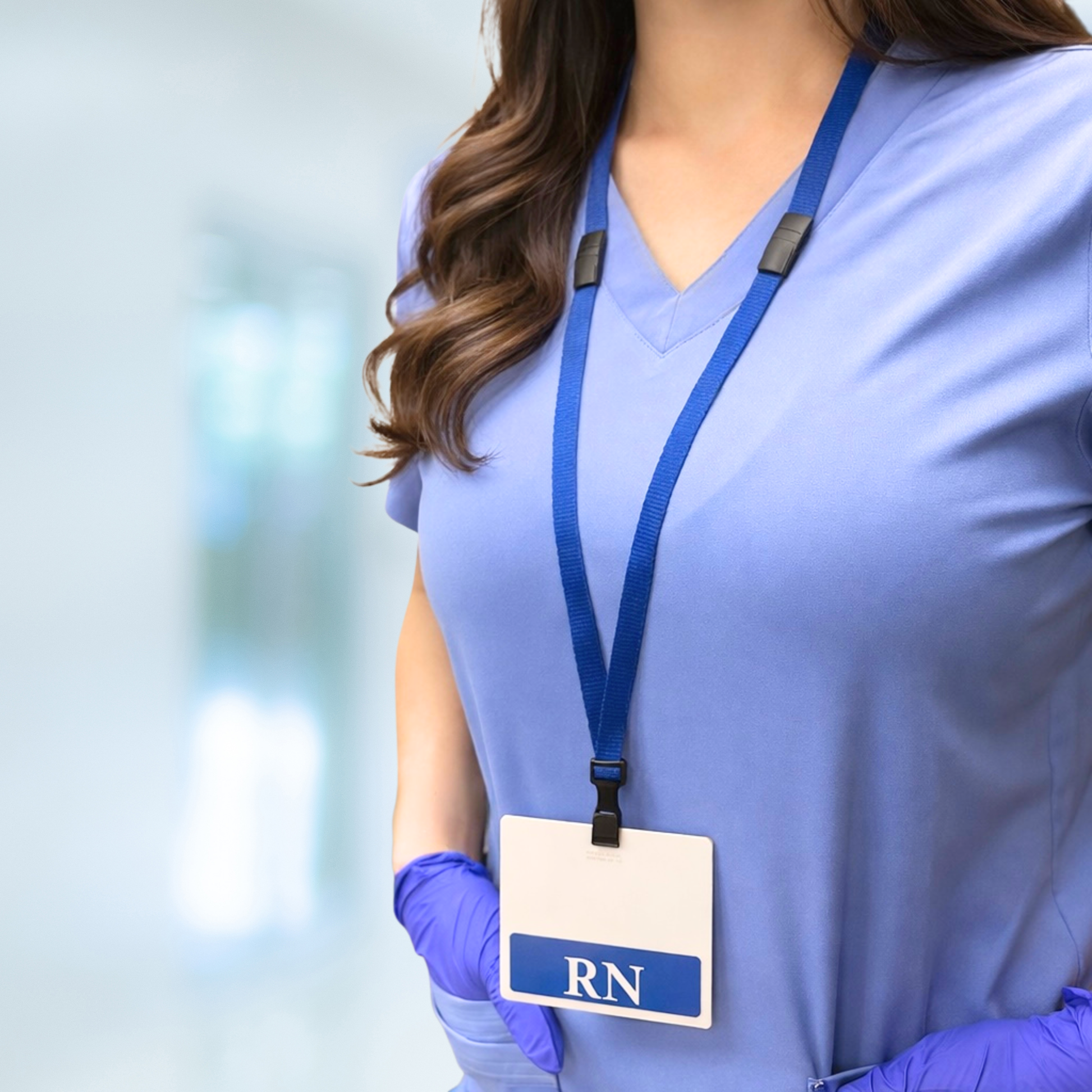 Person wearing blue scrubs wearing her lanyard clipped to a horizontal RN badge buddy, with a Triple Breakaway Lanyard with THREE Safety Breakaway Points (2137-300X), standing against a blurred background.