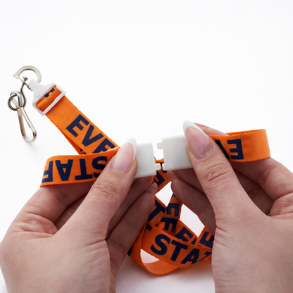 Orange breakaway event staff lanyard with j hookwristbands with "EVENT STAFF"text held by hands on a white background. Sold by Specialist ID.