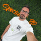A man with glasses and a beard takes a selfie in front of a leafy wall with orange cursive text. He wears a white t-shirt and an event badge on the Elastic No-Twist Neck Cord for ID Badge Holders (2140-15XX Series) for a casual yet official style.