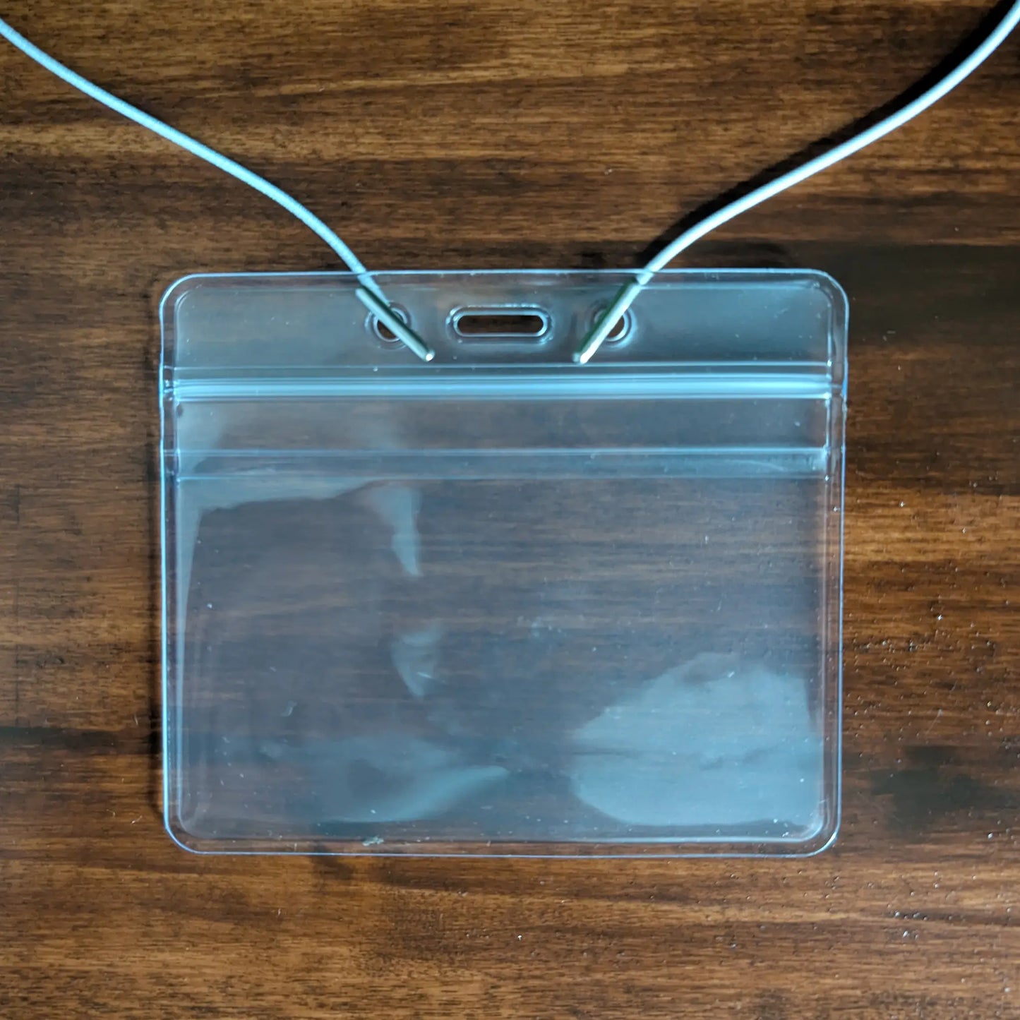 An Elastic No-Twist Neck Cord for ID Event Badge Holders (2140-15XX Series) is shown on a wooden surface.