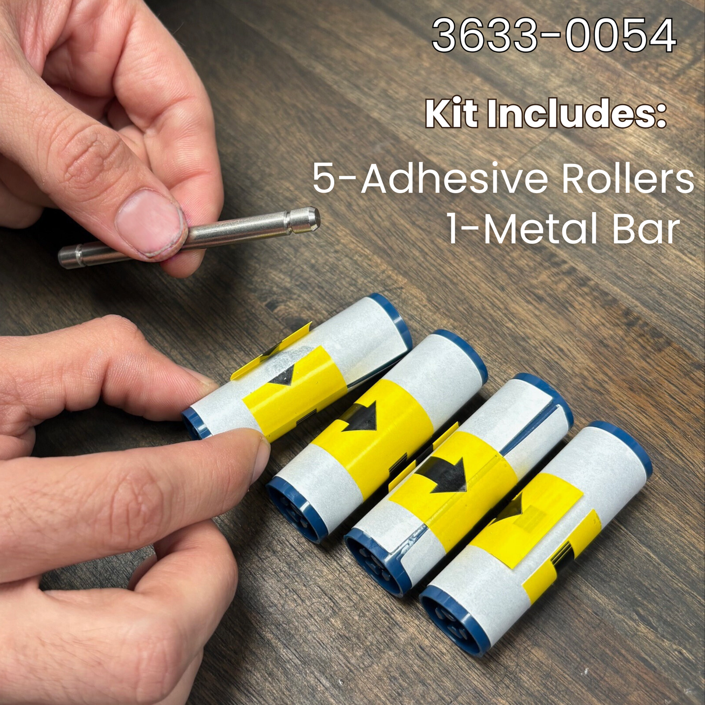 A hand holds a Magicard 3633-0054 Cleaning Roller Kit with Metal Bar (5 Pack) on a wood surface, showing 1 metal bar and 5 adhesive rollers—perfect for maintaining your Magicard ID card printer.