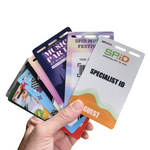 Hand holding various colorful ID cards with different designs and text.